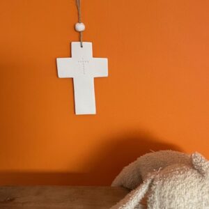 Croix murale en porcelaine blanche suspendue sur un mur de chambre